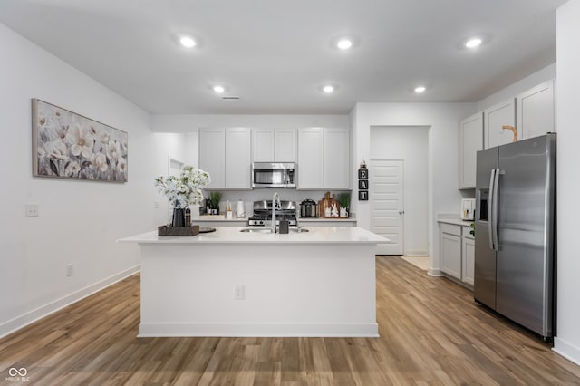 kitchen with a sink, stainless steel appliances, light wood-style flooring, and light countertops