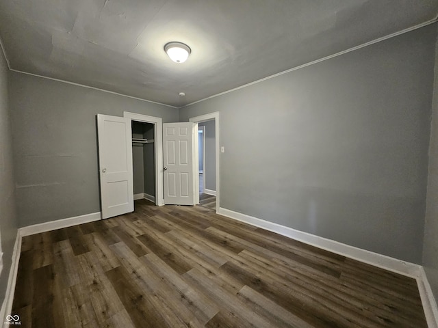 unfurnished bedroom with a closet, baseboards, and dark wood finished floors