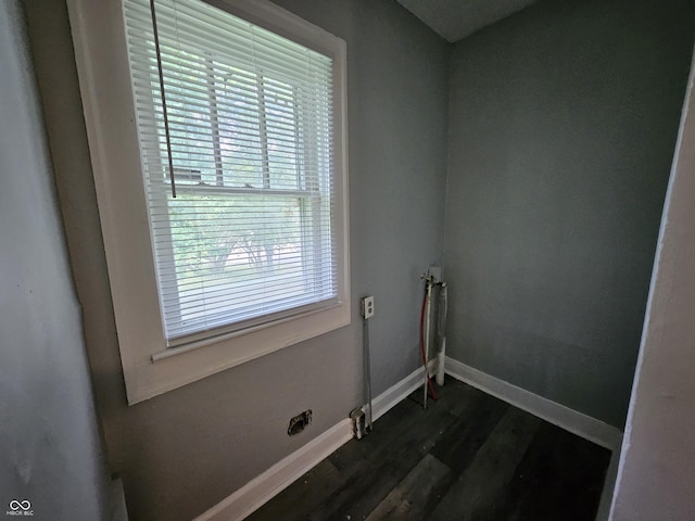 clothes washing area featuring dark wood finished floors and baseboards