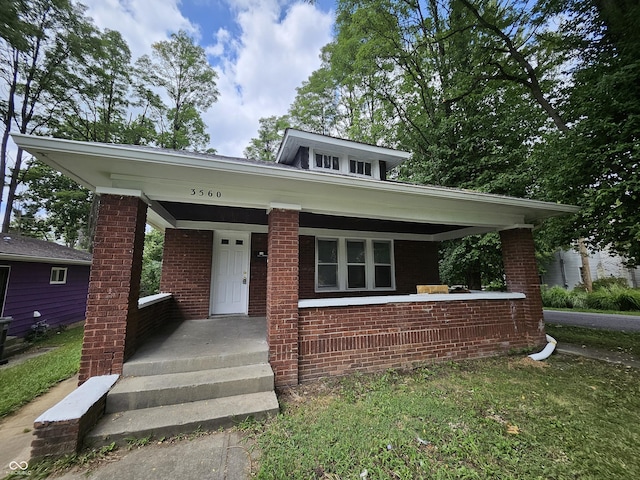 bungalow-style home featuring covered porch and brick siding