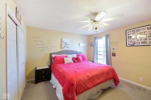 carpeted bedroom featuring ceiling fan, baseboards, a closet, and a textured ceiling