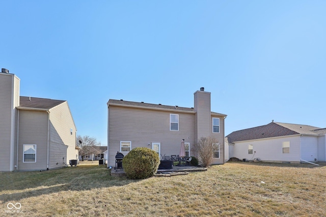 rear view of house with a patio, a yard, central AC unit, and a chimney