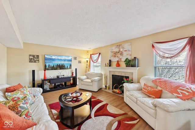 living area featuring a textured ceiling, wood finished floors, and a fireplace