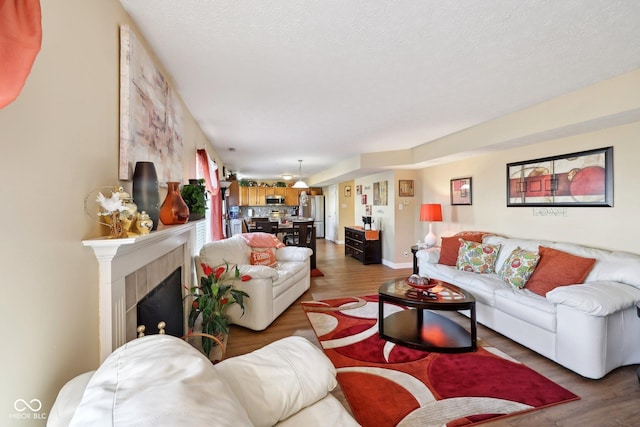 living area featuring a fireplace, wood finished floors, baseboards, and a textured ceiling