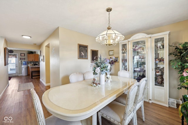 dining area with dark wood finished floors, an inviting chandelier, and baseboards