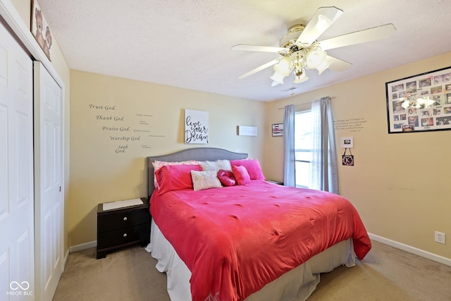 carpeted bedroom featuring a closet, a textured ceiling, baseboards, and a ceiling fan