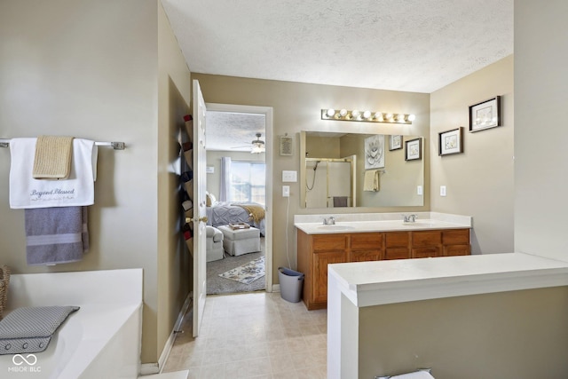 ensuite bathroom with double vanity, a stall shower, a textured ceiling, ensuite bath, and a sink