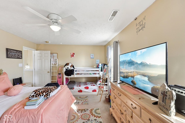 bedroom with ceiling fan, light colored carpet, visible vents, and a textured ceiling