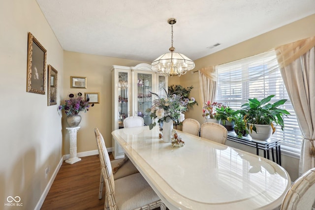 dining room featuring a notable chandelier, dark wood-style floors, visible vents, and baseboards