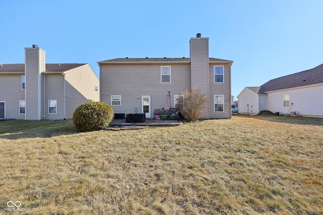 back of house featuring a lawn, a chimney, and a patio area