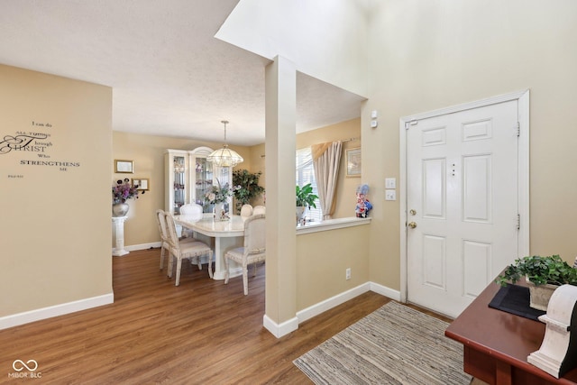 entryway with an inviting chandelier, wood finished floors, and baseboards