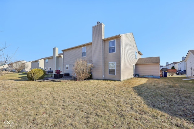 rear view of property featuring a patio, a lawn, and a chimney