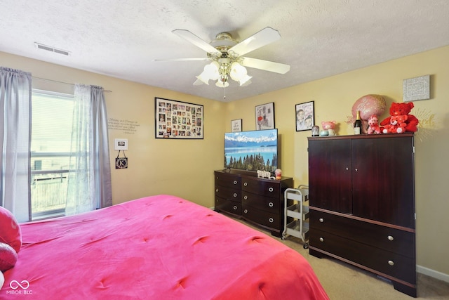 bedroom featuring visible vents, a textured ceiling, a ceiling fan, and carpet floors