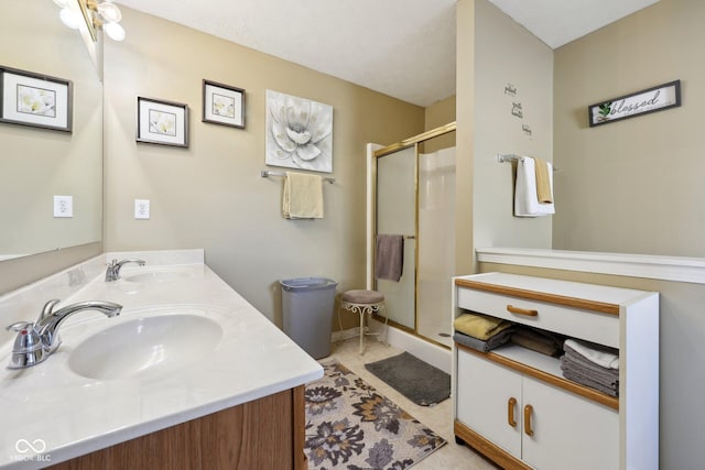 bathroom with a sink, double vanity, a shower stall, and tile patterned flooring