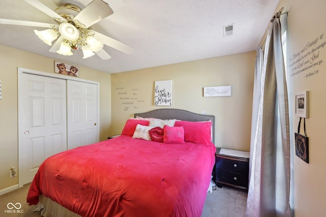 carpeted bedroom with a textured ceiling, visible vents, a closet, and ceiling fan