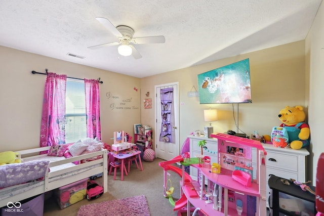 playroom featuring a ceiling fan, carpet, visible vents, and a textured ceiling