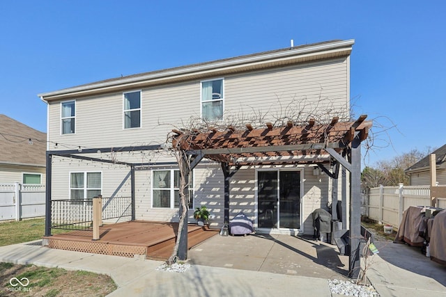 rear view of property featuring a wooden deck, a pergola, and fence