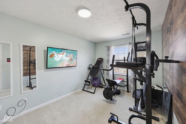 workout area featuring baseboards, visible vents, carpet floors, and a textured ceiling