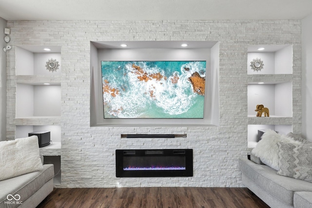 living room with a stone fireplace and wood finished floors