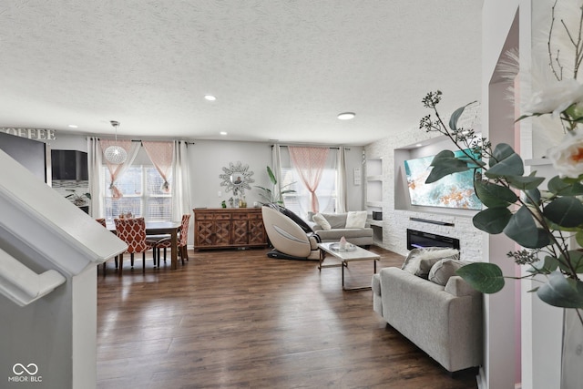 living area featuring a wealth of natural light, a fireplace, a textured ceiling, and dark wood-type flooring