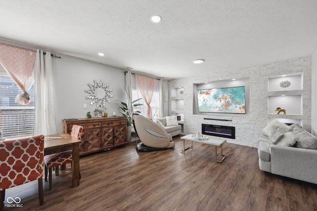 living room with a glass covered fireplace, built in features, a textured ceiling, and wood finished floors