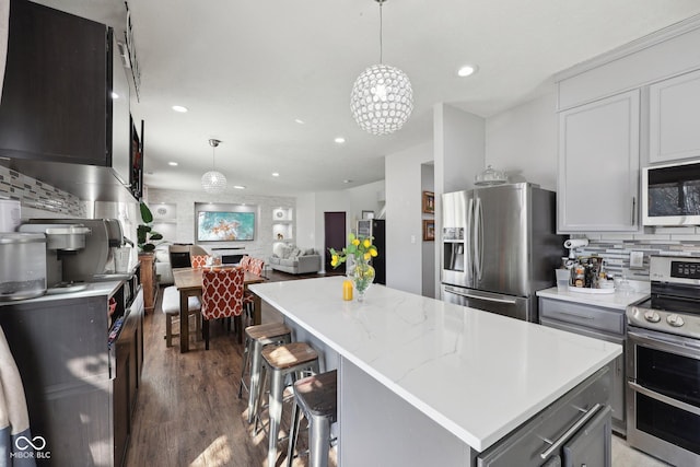 kitchen featuring wood finished floors, recessed lighting, appliances with stainless steel finishes, backsplash, and a center island