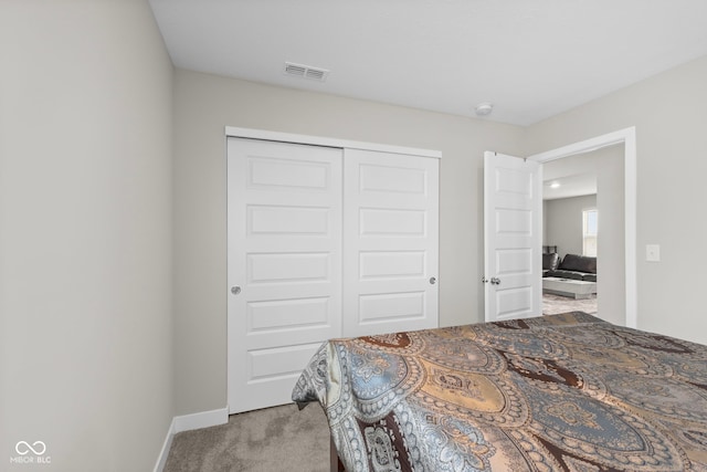 bedroom featuring a closet, visible vents, light colored carpet, and baseboards