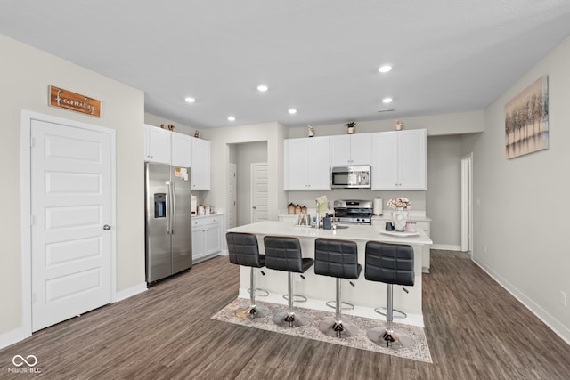 kitchen featuring dark wood-type flooring, baseboards, a breakfast bar area, white cabinets, and stainless steel appliances