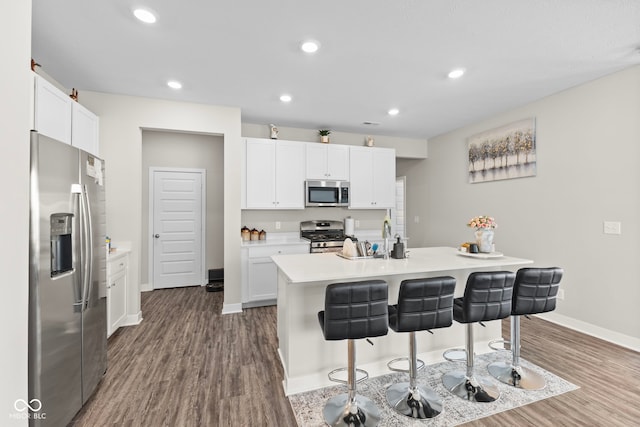 kitchen with dark wood finished floors, light countertops, a kitchen breakfast bar, and stainless steel appliances