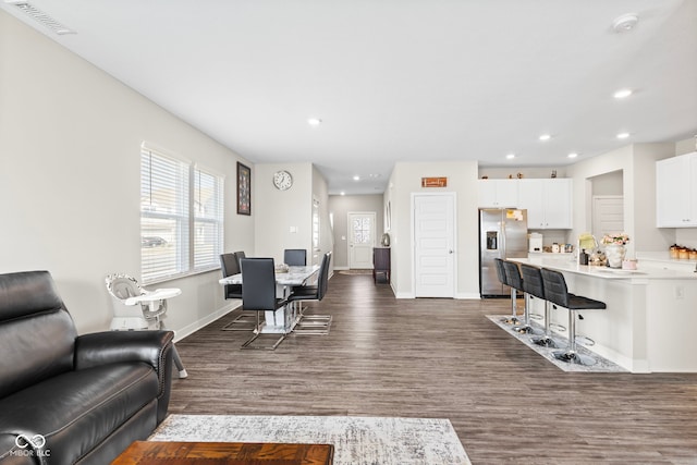 living room with visible vents, plenty of natural light, dark wood-type flooring, and baseboards