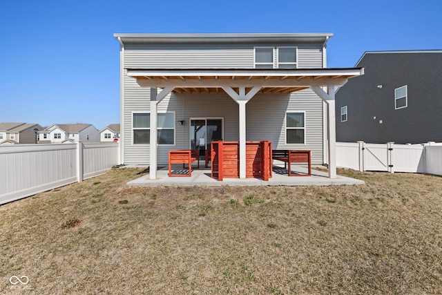 back of property featuring a gate, a lawn, a fenced backyard, and a patio area