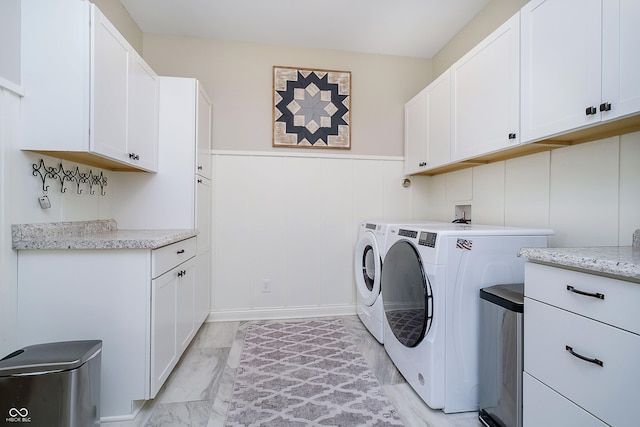 washroom with washer and dryer, cabinet space, a wainscoted wall, and marble finish floor