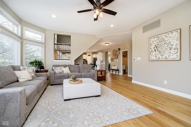 living room featuring wood finished floors, a ceiling fan, visible vents, and baseboards