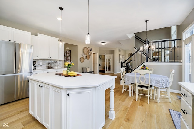 kitchen featuring light countertops, light wood-style flooring, freestanding refrigerator, and a kitchen island