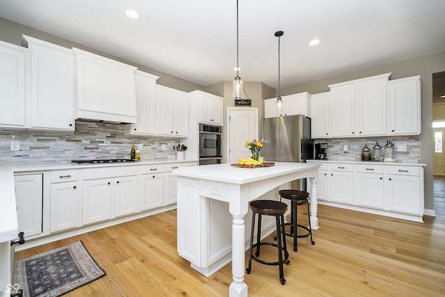 kitchen with a center island, white cabinets, stainless steel appliances, and light wood-type flooring