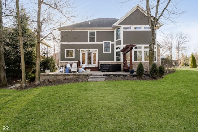 rear view of house featuring a yard, a pergola, stucco siding, a hot tub, and a patio area