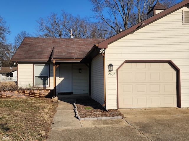 entrance to property featuring a garage, roof with shingles, and concrete driveway