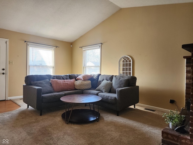 carpeted living area with visible vents, baseboards, a textured ceiling, and high vaulted ceiling