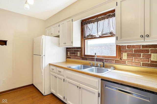 kitchen featuring light wood-type flooring, a sink, tasteful backsplash, white cabinets, and dishwasher