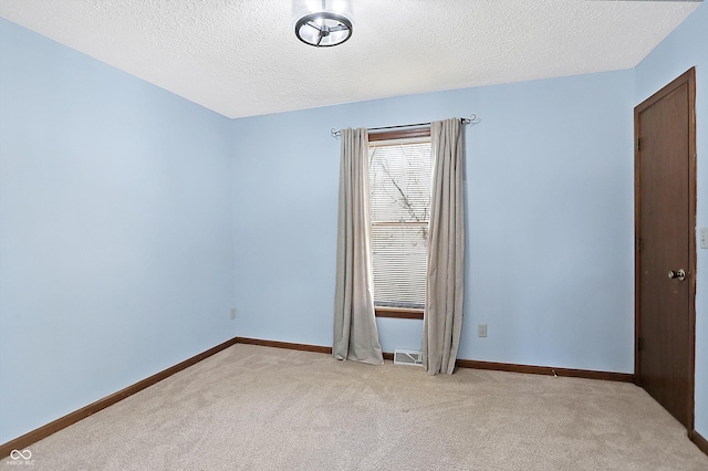 unfurnished room with a textured ceiling, baseboards, and light carpet