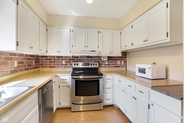 kitchen featuring under cabinet range hood, white cabinetry, and stainless steel appliances