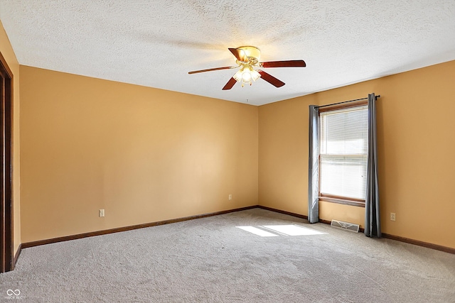 empty room with visible vents, a textured ceiling, carpet, baseboards, and ceiling fan