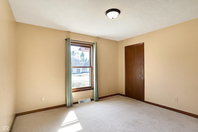 unfurnished room featuring visible vents, baseboards, light colored carpet, and a textured ceiling