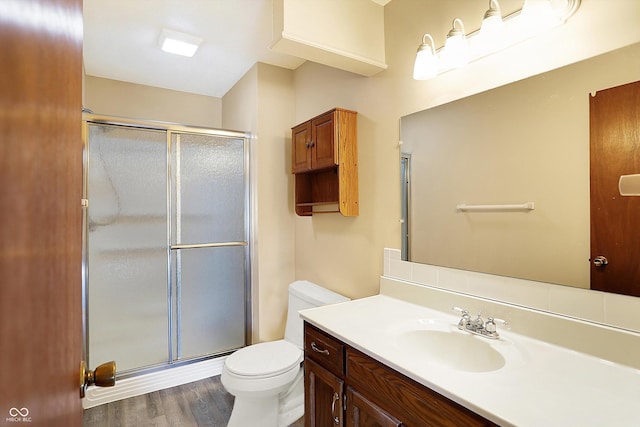 bathroom with vanity, a shower stall, toilet, and wood finished floors