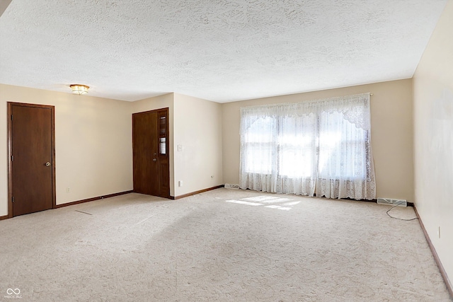 empty room with visible vents, baseboards, carpet, and a textured ceiling