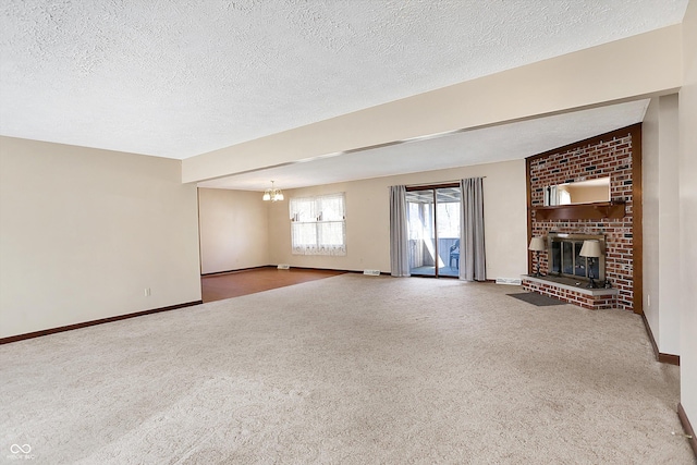 unfurnished living room with a chandelier, carpet flooring, a brick fireplace, and baseboards