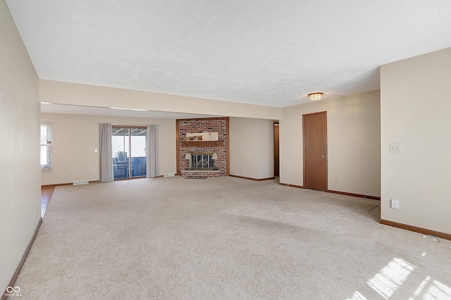 unfurnished living room with light colored carpet, a fireplace, baseboards, and a textured ceiling