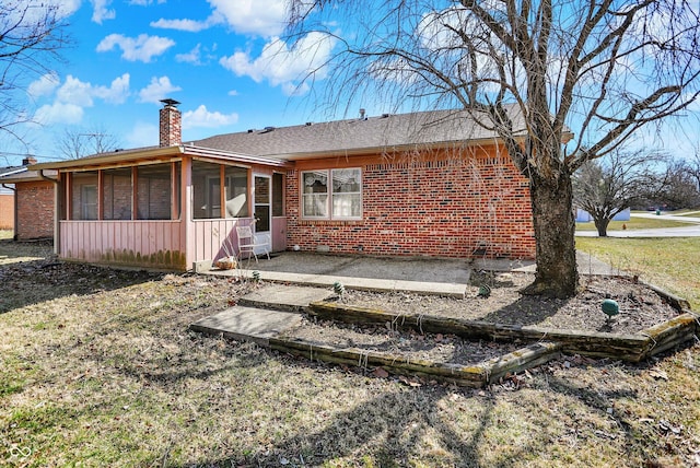 back of property featuring a patio, brick siding, a sunroom, and a chimney