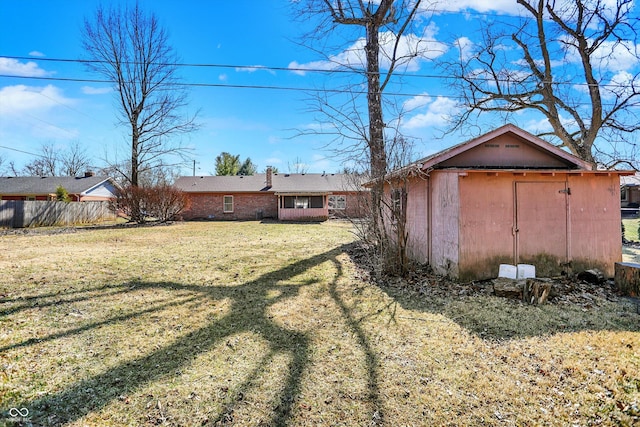 view of yard featuring an outbuilding, a storage shed, and fence