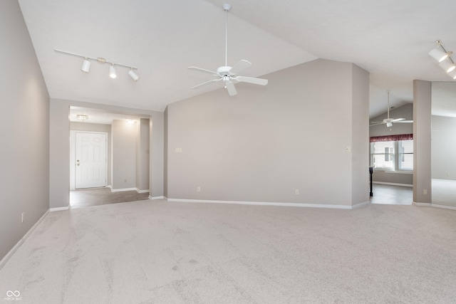 empty room featuring light carpet, track lighting, a ceiling fan, and vaulted ceiling